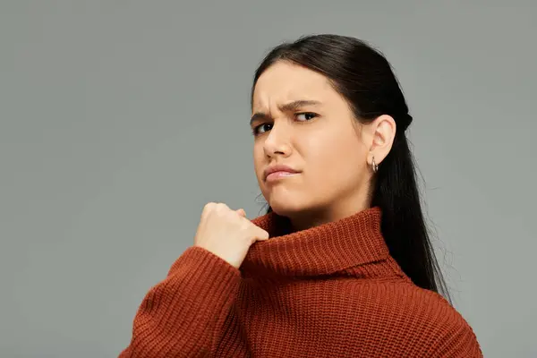A young woman in a rust sweater displays a captivating emotional expression in a minimalist setting. — Stock Photo