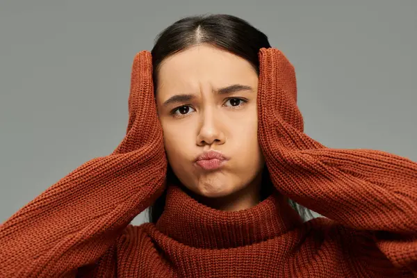 A young woman displays her emotions with a pout, hands on her head, in a cozy setting. — Stock Photo