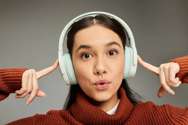 A young woman displays excitement while wearing headphones and a fashionable outfit. — Stock Photo