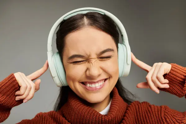 A young woman joyfully listens to music, wearing headphones and showcasing her stylish outfit. — Stock Photo
