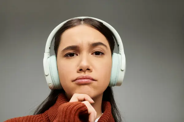 Una giovane donna elegante con le cuffie sembra contemplativo, esprimendo profonda emozione e pensiero. — Foto stock