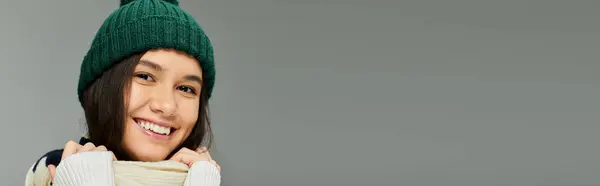 A cheerful young woman, dressed in cozy winter fashion, smiles brightly while holding her scarf. — Stock Photo