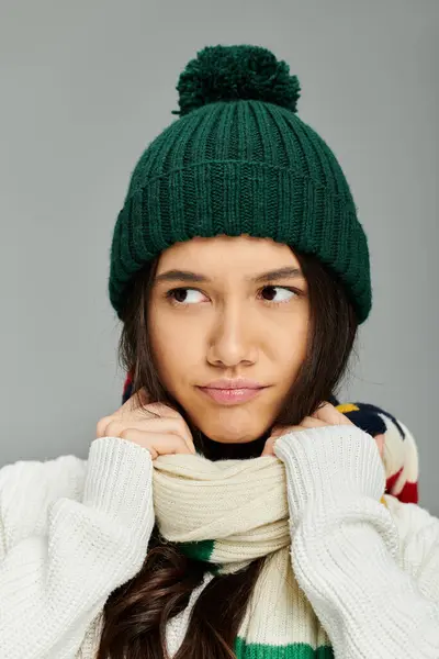 A young woman expresses emotions while adjusting her scarf, enveloped in warmth and style. — Stock Photo