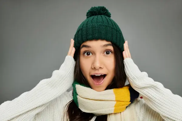 A young woman in a cozy hat and scarf expresses excitement with a surprised look. — Stock Photo
