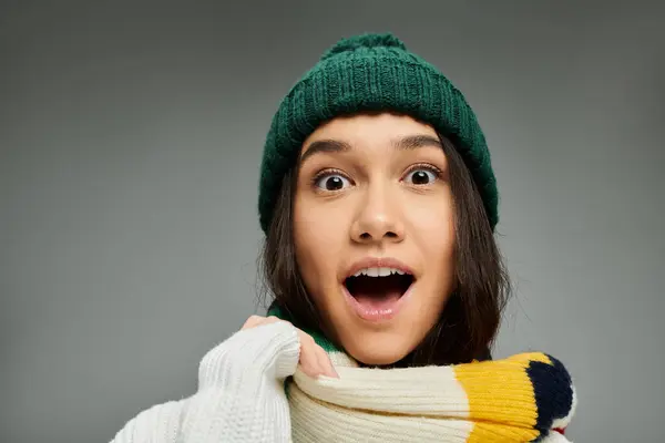 A young woman with a bright expression showcases her stylish winter outfit while looking amazed. — Stock Photo
