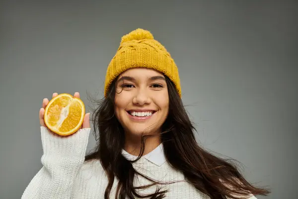 Uma mulher elegante expressa alegria ao mostrar uma fruta laranja vibrante em sua mão. — Fotografia de Stock