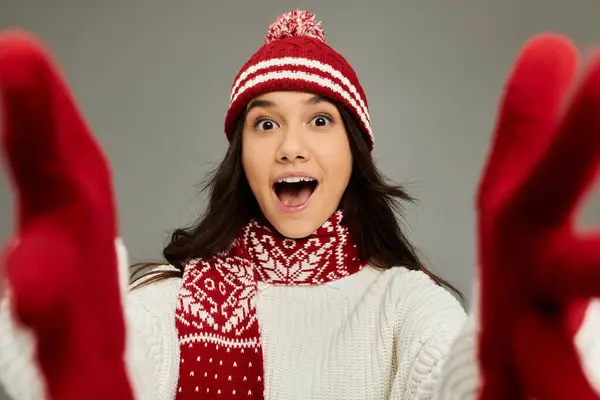 Uma jovem mulher em uma roupa aconchegante vermelho e branco exibe alegremente seu espírito de inverno brincalhão. — Fotografia de Stock