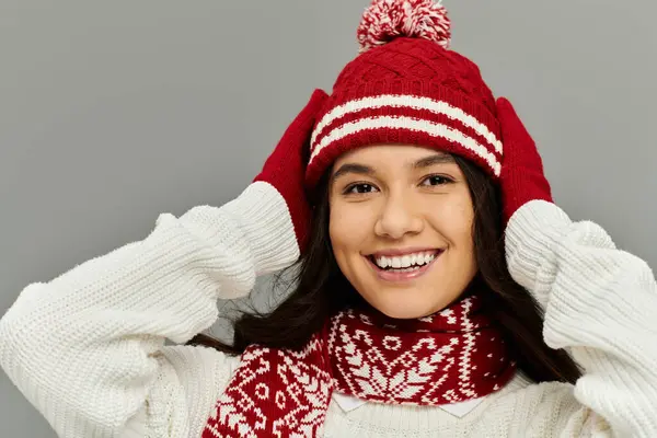 A young woman expresses joy while playfully adjusting her winter hat and gloves. — Stock Photo