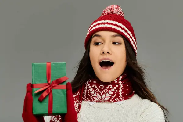 Aufgeregte junge Frau im gemütlichen Winteroutfit erfreut sich an einem festlichen Geschenk. — Stockfoto