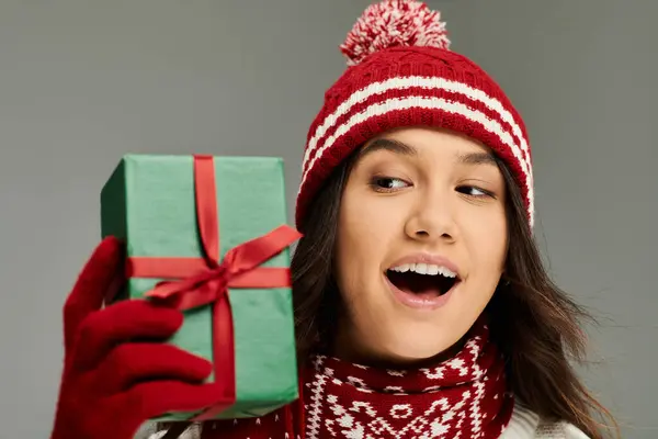 A young woman in stylish winter wear expressively reacts to a holiday gift while celebrating. — Stock Photo
