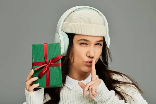 Giovane donna emotiva in abbigliamento elegante chiede giocosamente silenzio mentre tiene in mano un regalo. — Foto stock