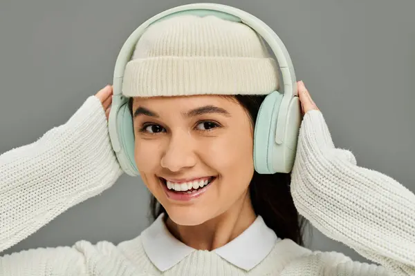 Eine fröhliche junge Frau mit Strickmütze und Kopfhörern genießt Musik, die Emotionen ausstrahlt. — Stockfoto