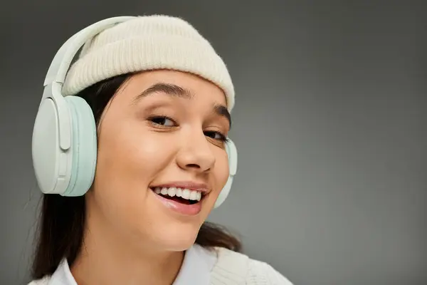 A smiling young woman enjoys music, flaunting her stylish outfit and vibrant spirit. — Stock Photo