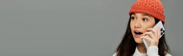 A young woman in fashionable attire excitedly talks on the phone, showing her emotions vividly. — Stock Photo