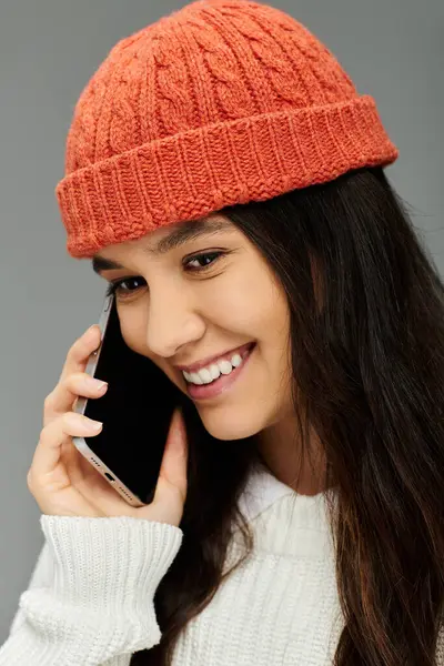 A young woman in a cozy winter outfit enjoys a cheerful phone conversation, radiating warmth. — Stock Photo