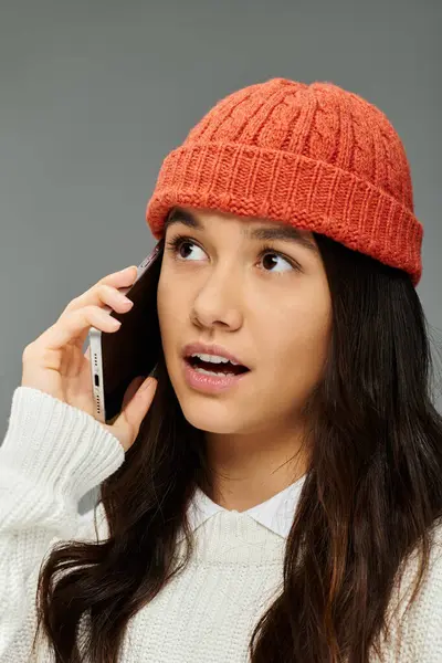 Uma jovem mulher em uma roupa elegante expressa suas emoções enquanto fala ao telefone. — Fotografia de Stock