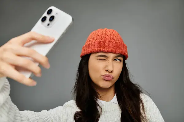 A vibrant young woman showcases her playful side while capturing a fun moment with her phone. — Stock Photo