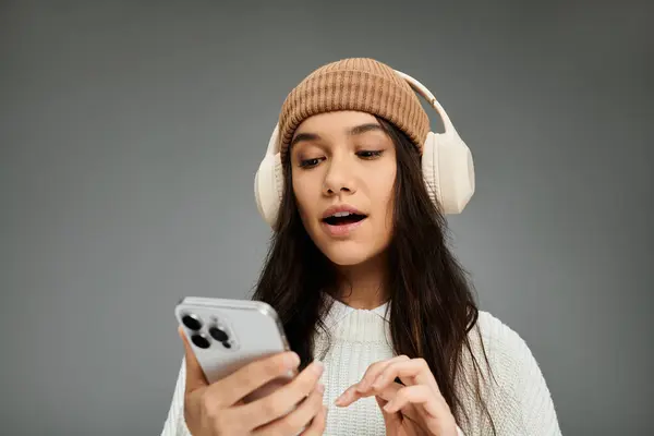 Uma jovem elegante expressa emoções enquanto se envolve com seu telefone, desfrutando de música. — Fotografia de Stock