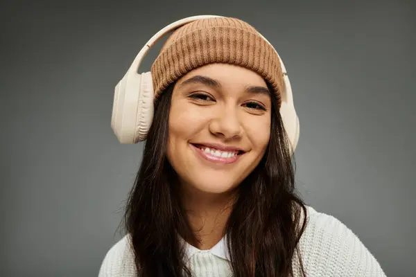 A vibrant young woman radiates joy with a trendy outfit and headphones in a cozy atmosphere. — Stock Photo