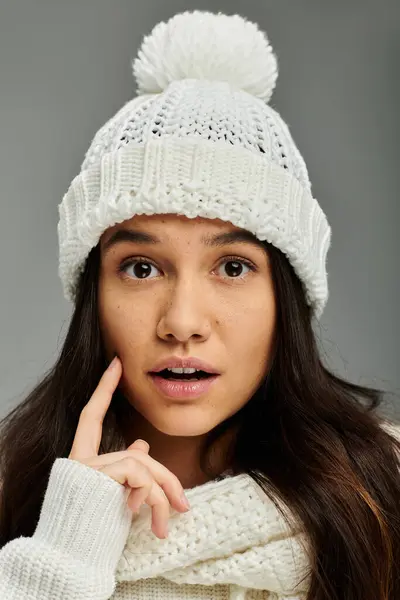 Una giovane donna con lunghi capelli scuri sembra sorpresa in un cappello caldo e sciarpa. — Foto stock
