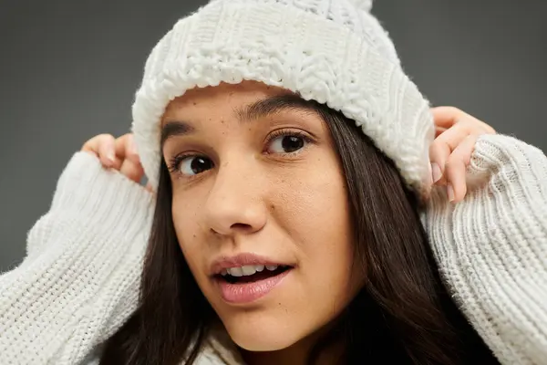 Una bonita joven ajusta su elegante sombrero de invierno, mostrando su expresión emocional y su atuendo. - foto de stock