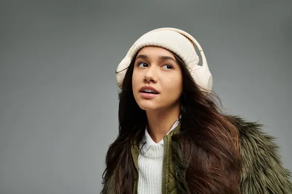 A stylish young woman gazes thoughtfully, showcasing her winter fashion and headphones. — Stock Photo