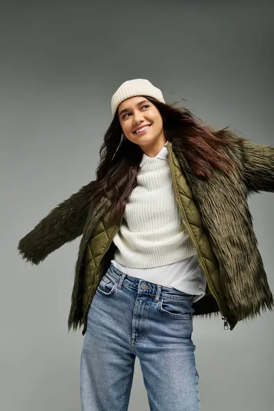 A young woman with a joyful expression showcases her trendy winter outfit with flair and confidence. — Stock Photo