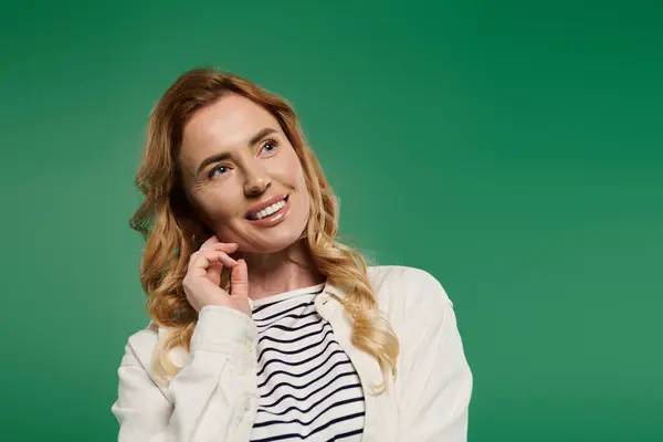 A woman with beautiful curly hair wears casual clothing, thoughtfully smiling against a bright green background. — Stock Photo