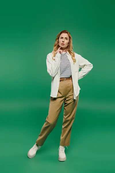 A stylish woman with curly hair stands in casual attire, expressing a moment of contemplation in front of green. — Stock Photo
