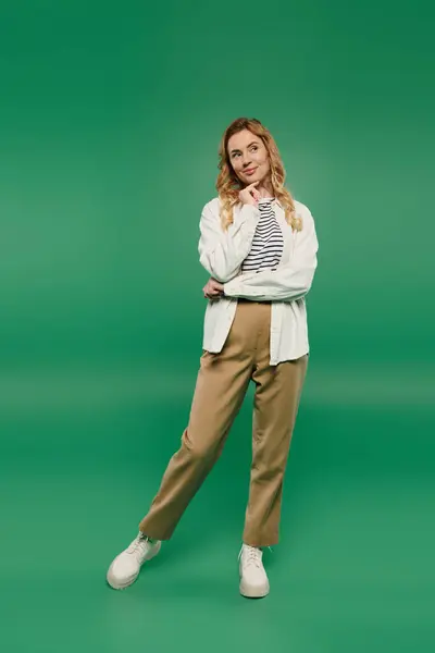 A woman with beautiful curly hair stands confidently, sporting a casual outfit, set against a lively green background. — Stock Photo
