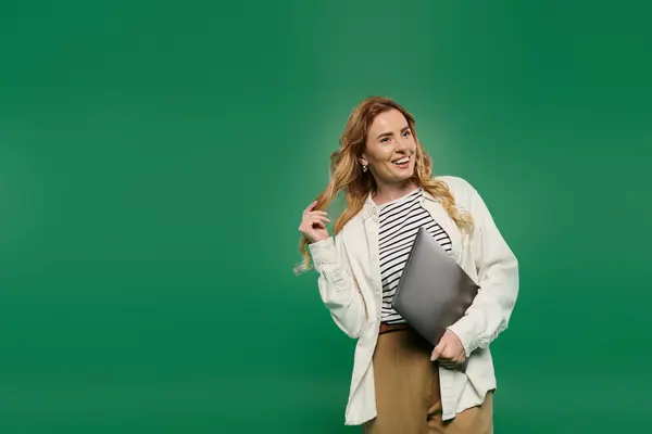 A cheerful woman with curly hair showcases her vibrant style while playfully posing against a green backdrop. — Stock Photo