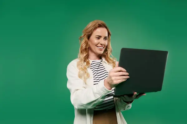 A cheerful woman with gorgeous curls interacts with her laptop, radiating positivity in a lively setting. — Stock Photo