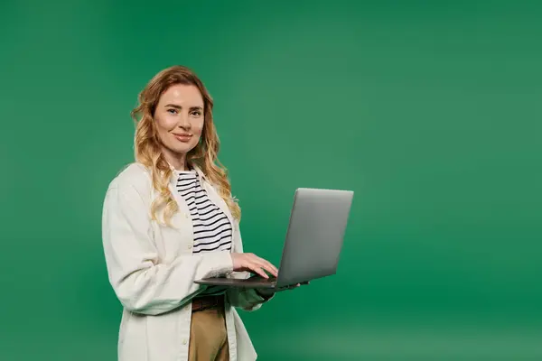 A stylish woman with curly hair engages with her laptop, showcasing focus and creativity in a bright setting. — Stock Photo