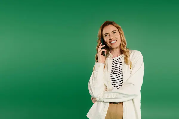 A casual, curly-haired woman enjoys a joyful phone conversation while smiling brightly. — Stock Photo