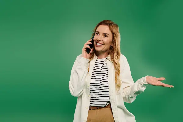 Uma mulher alegre com cabelos encaracolados bate-papos energeticamente em seu telefone, expressando emoção em traje casual. — Fotografia de Stock