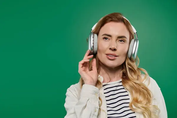A stylish woman with beautiful curls expresses joy listening to music, immersed in her own world of sound. — Stock Photo