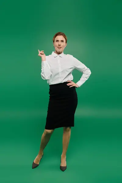 A poised woman in a stylish white shirt shows confidence while standing against a vibrant green background. — Stock Photo