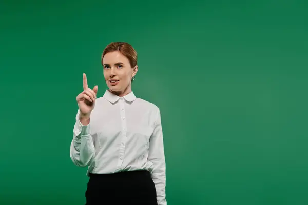 A professional woman in a white shirt gestures thoughtfully against a vibrant green background. — Stock Photo