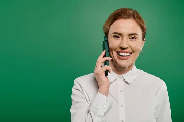 Vestida elegantemente, uma mulher sorri enquanto discute em seu telefone, irradiando profissionalismo e calor. — Fotografia de Stock