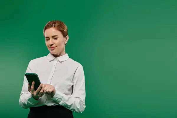 A professional woman dressed in a white shirt interacts with her smartphone in a lively environment. — Stock Photo