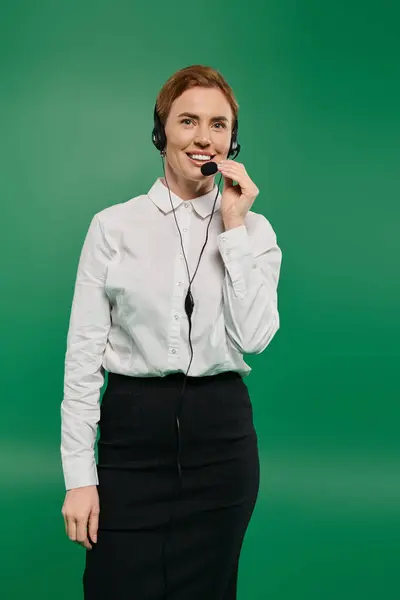 A confident woman in a crisp white shirt is speaking through a headset, ready to assist callers. — Stock Photo