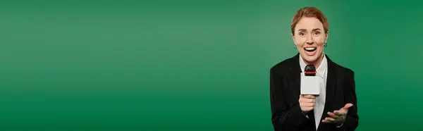 A dynamic presenter in stylish black attire interacts enthusiastically with microphone in hand. — Stock Photo