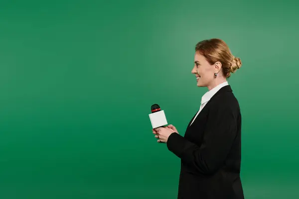 With a confident smile, the presenter stands on a green backdrop, ready to engage viewers on air. — Fotografia de Stock