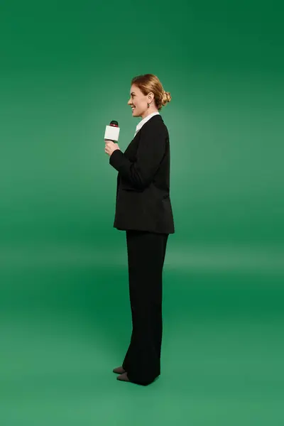 A stylish TV presenter stands confidently on a bright green background, exuding professionalism. — Stock Photo