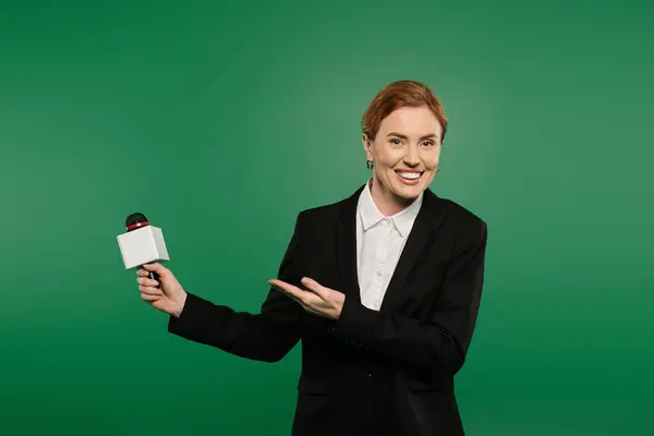 A confident presenter in black formal wear invites viewers to connect from a lively green backdrop. — Stock Photo