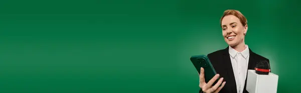 Зачарований телеведучий стоїть зі смартфоном і мікрофоном на яскраво-зеленому фоні. — Stock Photo