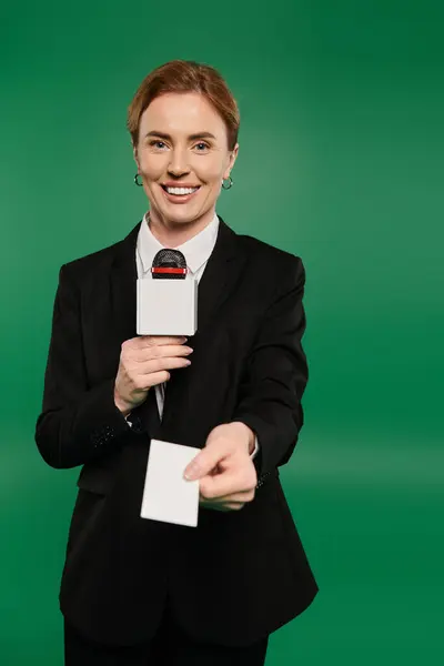 The TV presenter, dressed in elegant black, enthusiastically addresses an audience with a microphone. — Stock Photo