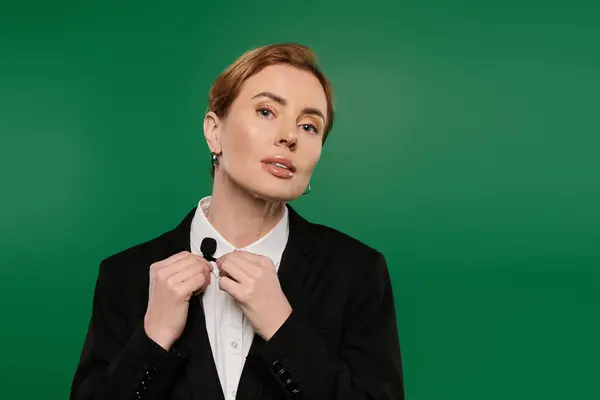 A dapper TV presenter in black formal wear exudes confidence while prepping for a broadcast in a vibrant setting. — Stock Photo