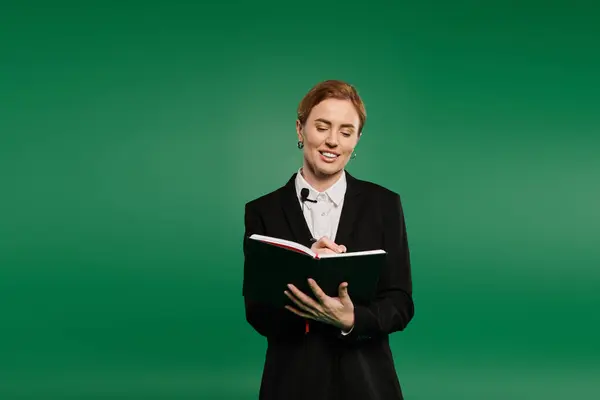 A charismatic presenter in black formal attire shares insights in front of a bright green background. — Fotografia de Stock