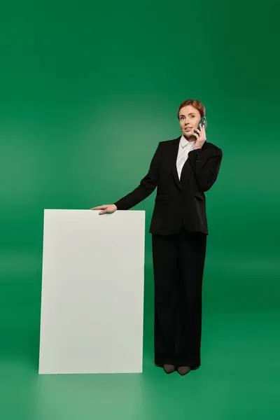 A stylish TV presenter dressed in black formal wear against a lively green background. — Stock Photo